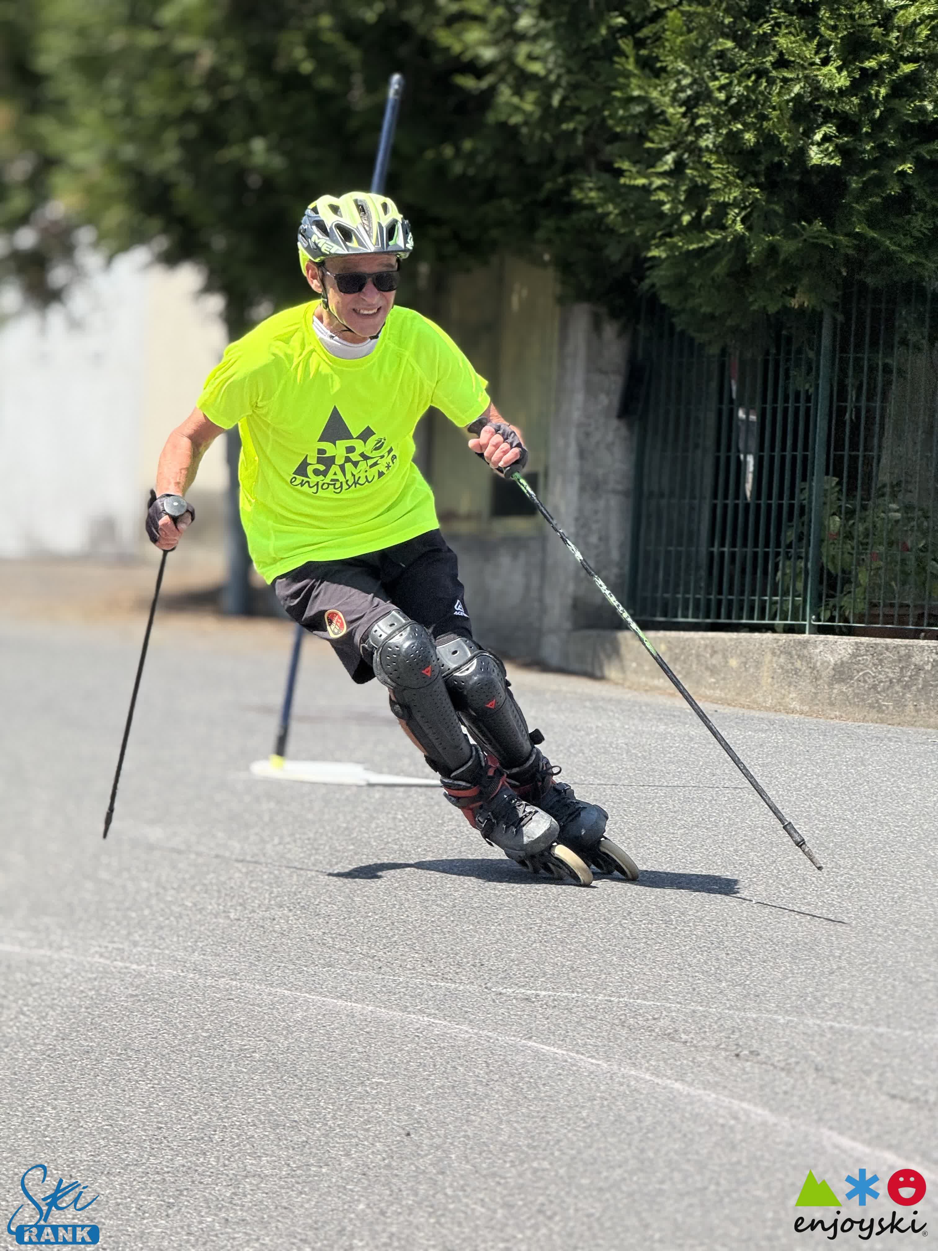 Uomo in maglia gialla fluo pratica pattinaggio in linea con bastoncini su strada asfaltata.