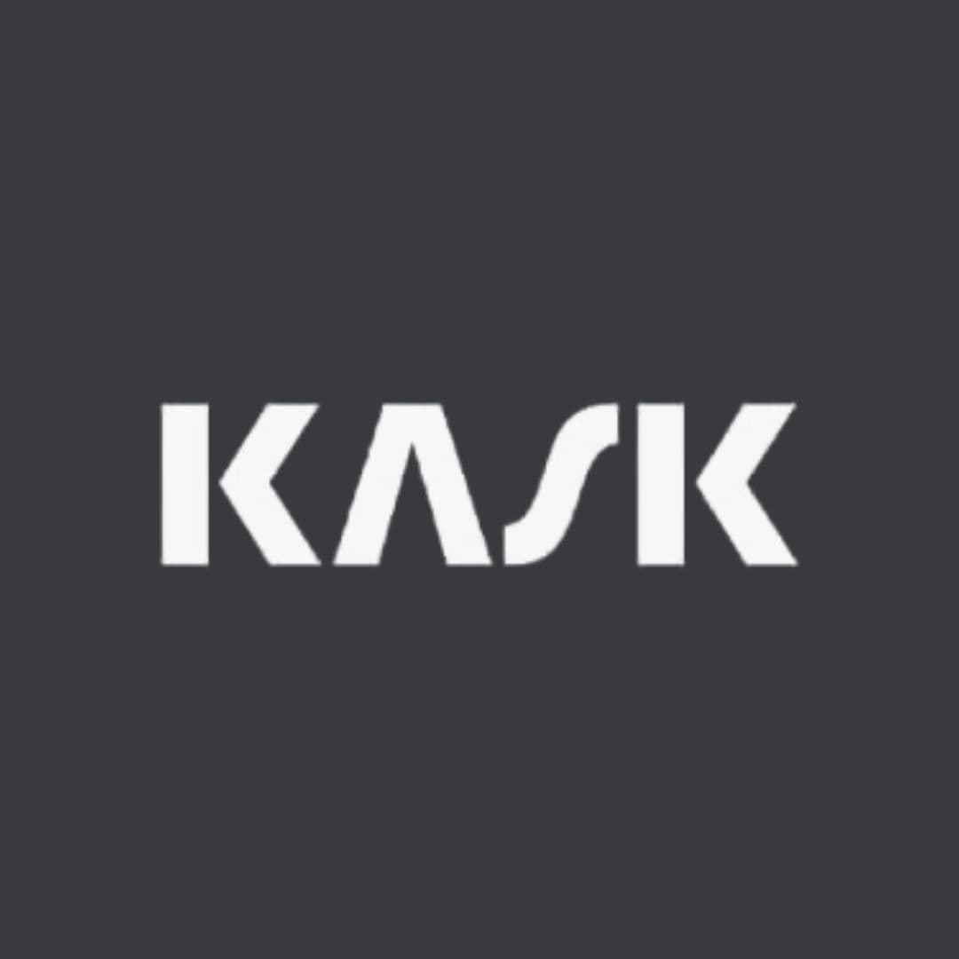 Logo KASK bianco con lettere stilizzate e geometriche su uno sfondo grigio scuro uniforme.