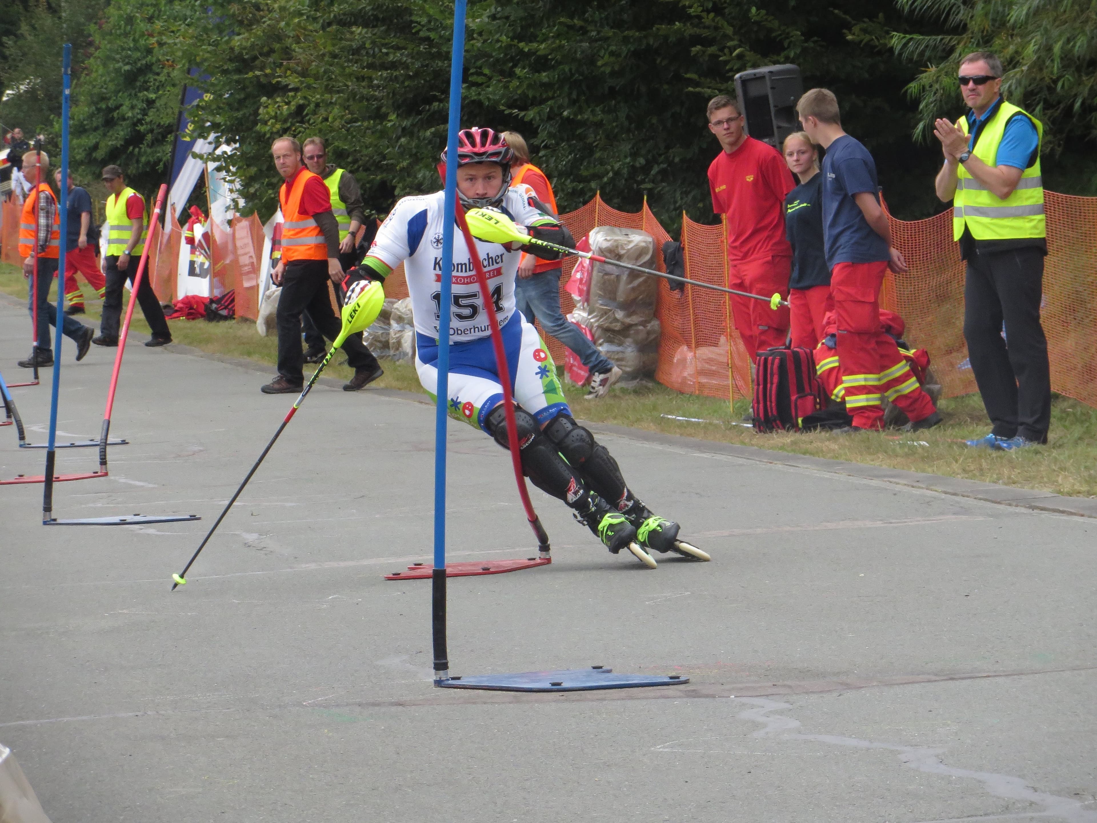 Atleta di pattinaggio in linea che affronta una curva di slalom tra pali blu.
